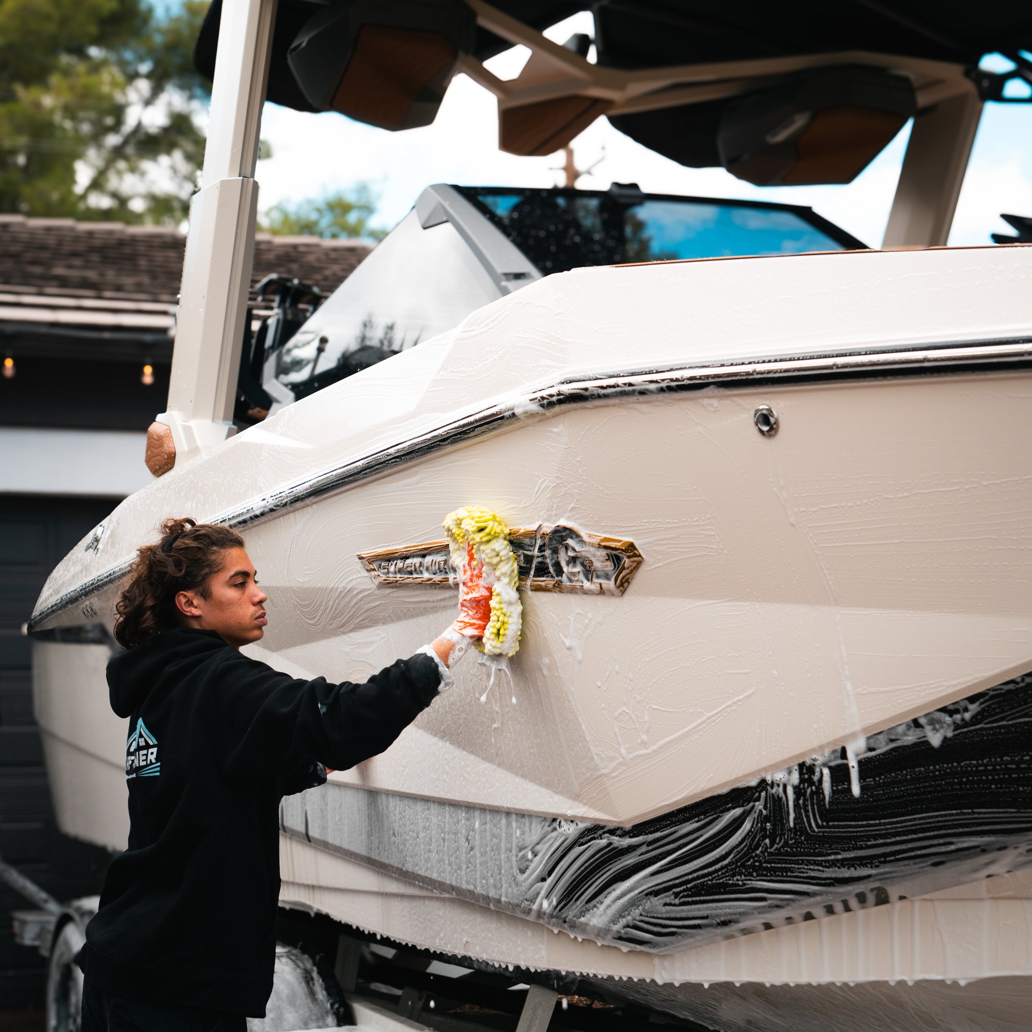 Pure Power Detailing contractor washing the side of a white Nautique boat with thick foam and a microfiber mitt during a professional marine detailing service in Phoenix, Arizona